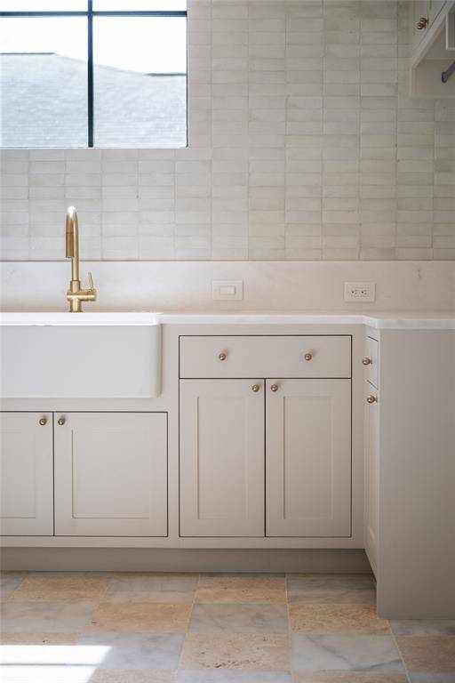 This thoughtful design of the laundry room showcases Elevare's attention to both function and elegance, featuring a luxurious marble countertop paired with a handcrafted brass faucet. The calming, neutral tones of the cabinetry and the unique tile work elevate the space, turning a practical room into a serene retreat.