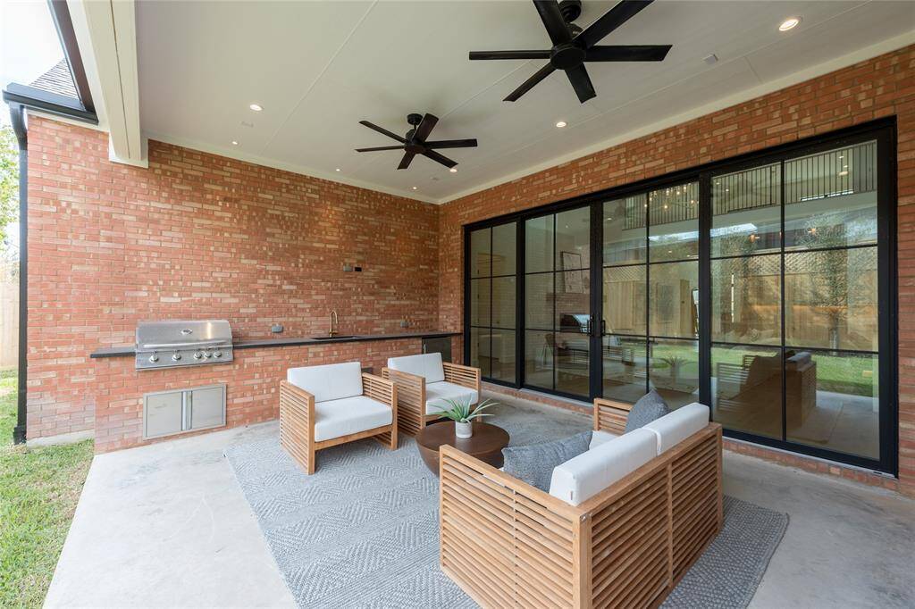 This covered outdoor space, part of an Elevare-built home, with summer kitchen, sink and fridge is a perfect blend of comfort and luxury.