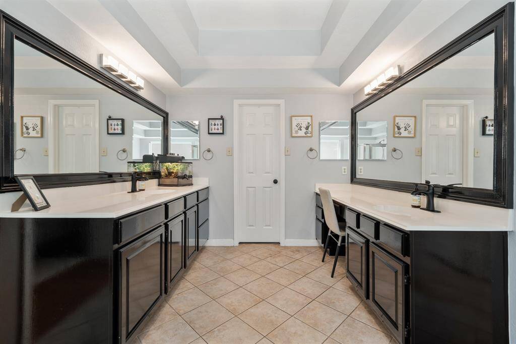 The primary bathroom is complete with two full vanities and framed mirrors.