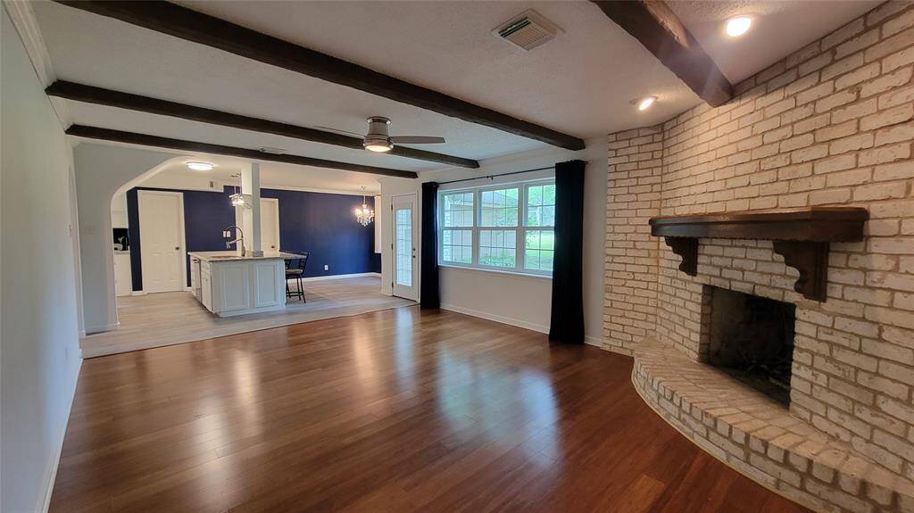 The family room boasts beamed ceilings, wood floors, and a brick fireplace.