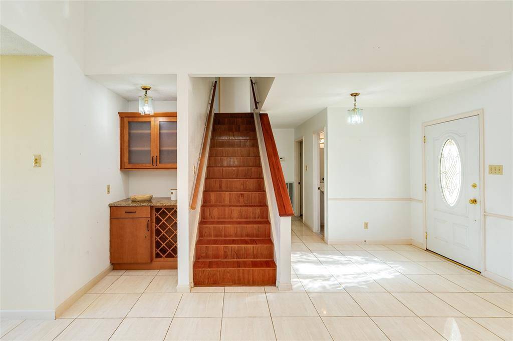 Dry bar with wine refrigerator and stairs to upper level.
