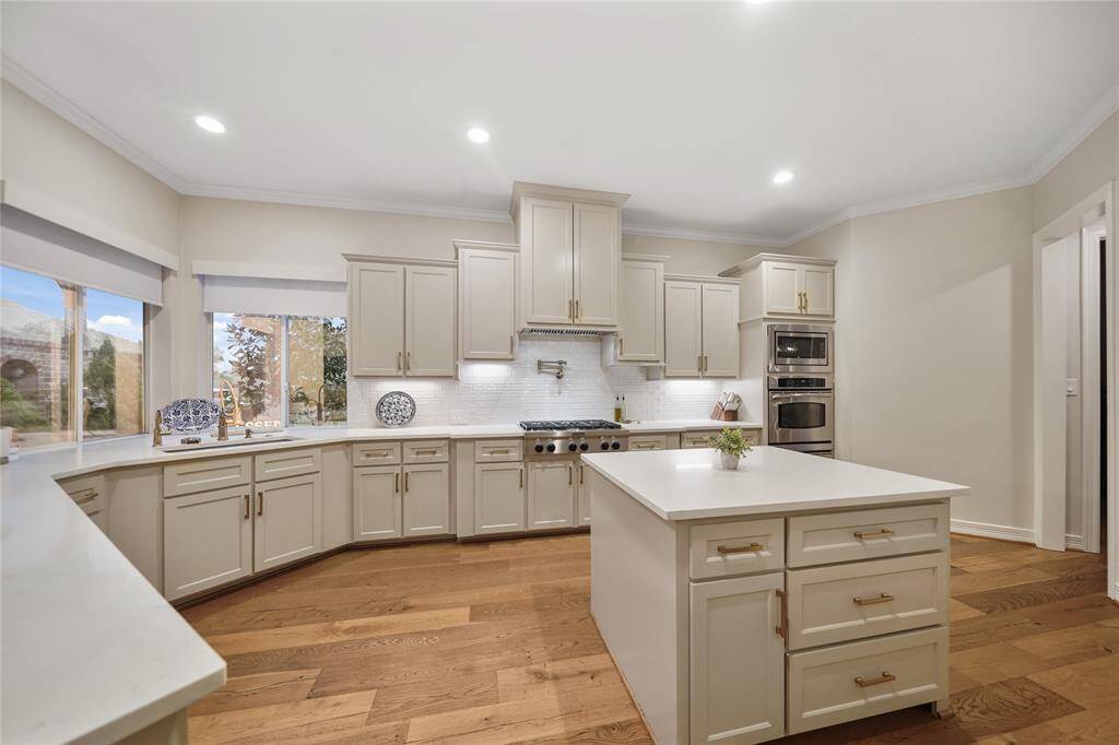 The spacious gourmet island kitchen is a culinary enthusiast’s dream, boasting quartz countertops, abundant cabinets, a Sub-Zero refrigerator, double ovens, a gas stovetop, and a walk-in pantry. A thoughtfully designed butler’s area with a wine fridge adds functionality and elegance
