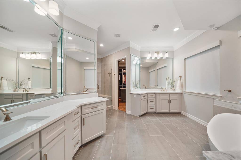 The spa-like bathroom includes a soaking tub, separate vanities, a large walk-in shower, and a custom closet complete with a large island and plenty of storage, ensuring all your wardrobe and accessory needs are met.
