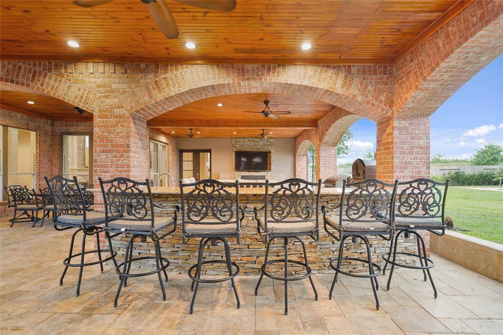 Absolutely Beautiful Outdoor Covered Patio with Brick Arched Columns, Granite Counter Bar! Wood Plank Ceilings, Tons of Lights, Fans and Multiple Dining and Lounge Spaces.