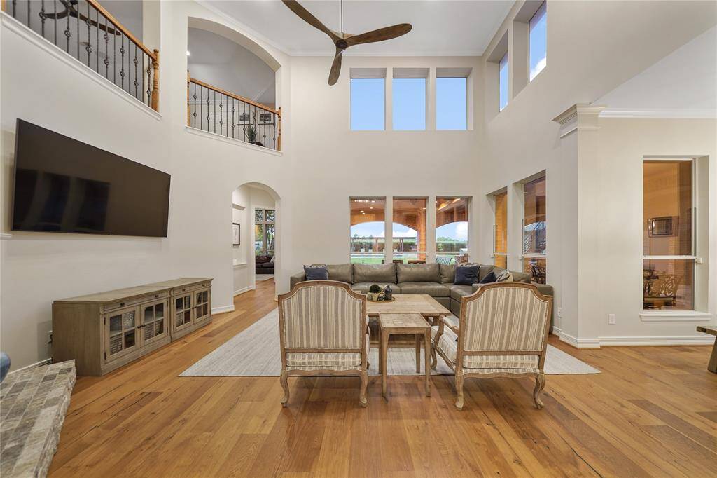 A two-story family room with floor-to-ceiling windows and a beautiful stone fireplace.