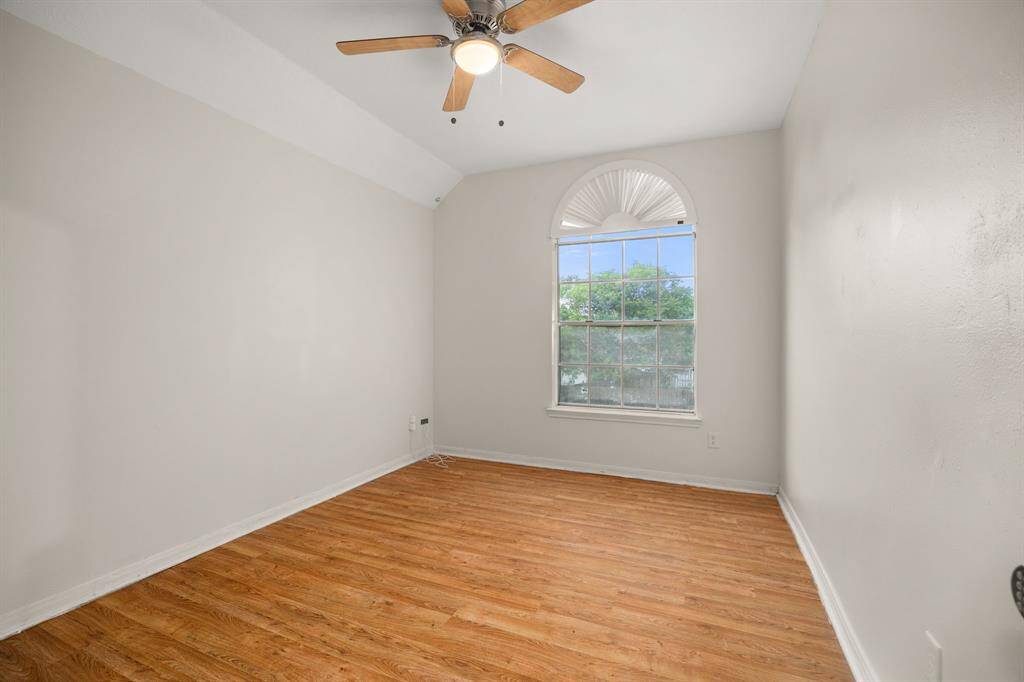 Bright and airy bedroom with vaulted ceilings, wood-style floors, and a beautiful arched window that brings in tons of natural light.