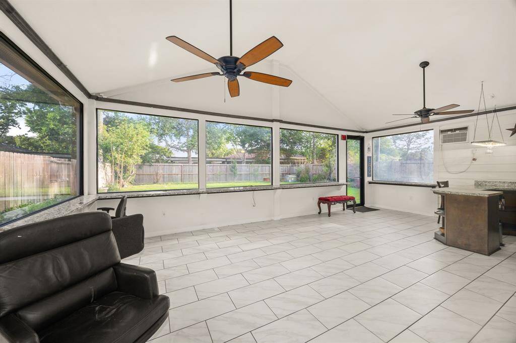 Massive sunroom with panoramic windows, tile flooring, and dual ceiling fans - ideal for entertaining, lounging, or turning into your own indoor-outdoor paradise.