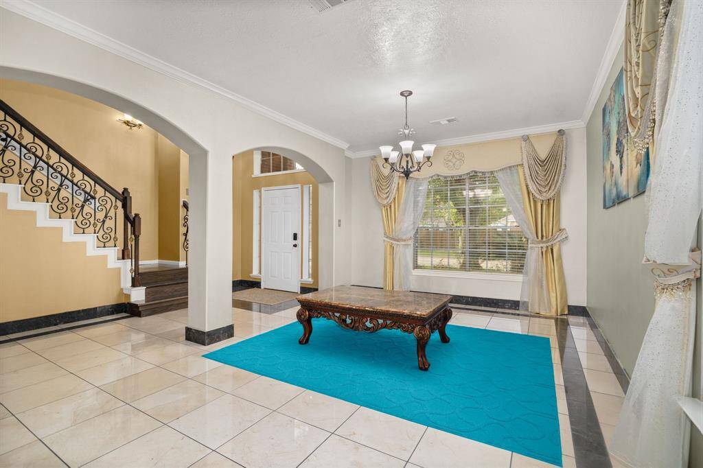 Step into an elegant foyer with grand columns, a curved staircase, and natural light pouring in through large windows - setting the tone for the rest of the home.