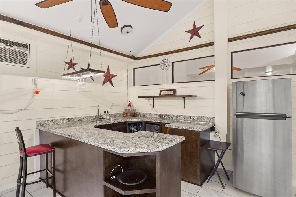 Custom bar setup with granite countertops, pendant lightning, and a mini fridge - perfect for game nights, cocktails, or creating your own in-home lounge vibe.