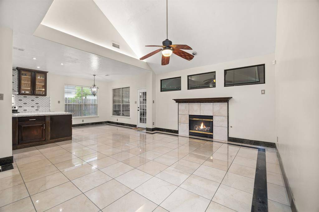 Spacious living area with soaring ceilings, sleek Italian marble flooring, and a modern gas fireplace - perfect for cozy nights or entertaining in style.