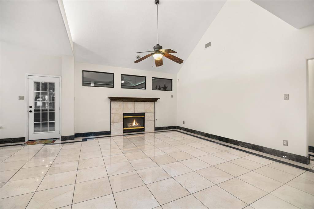 Vaulted ceilings, a cozy gas fireplace, and sleek marble tile floors make this living room the heart of the home - open, airy, and full of potential.