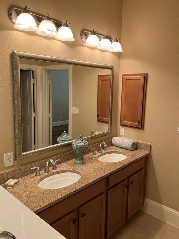 Double granite vanity with plenty of lighting in primary bath