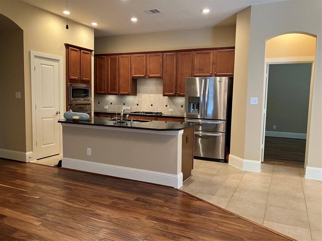 Gorgeous kitchen features granite countertops and rich wood cabinetry, with sliders in most cabinets and the entire pantry.