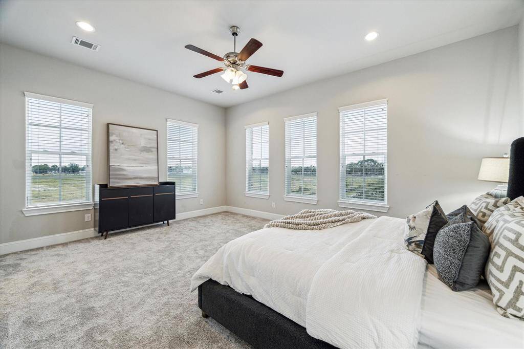 Large primary bedroom with fresh carpet and extra windows, providing an abundance of natural light