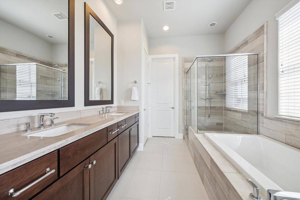 En suite primary bathroom with granite counters, double sinks, walk-in shower, and separate garden tub.
