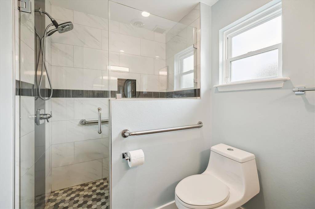 Large tiled walk-in shower with timeless hexagonal tile flooring and frameless glass enclosure.