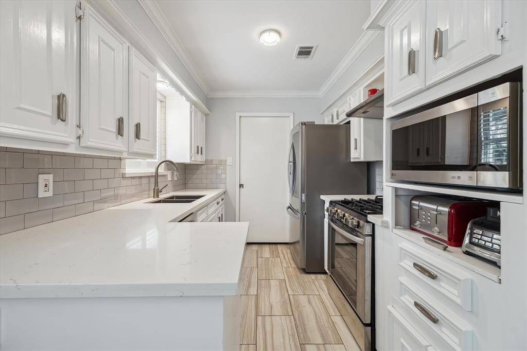 Remodeled kitchen with white cabinetry, subway tile backsplash, quartz countertops, and stainless appliances.