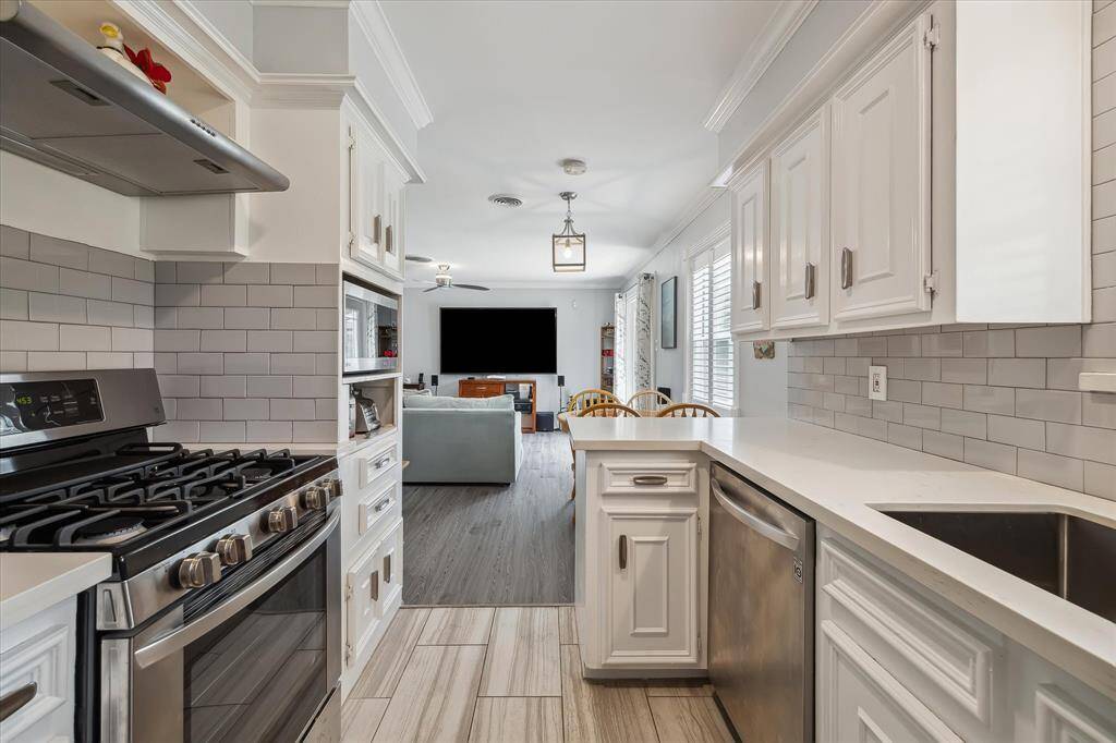 Alternate view of updated kitchen highlighting the stainless-steel appliances and quartz countertops.