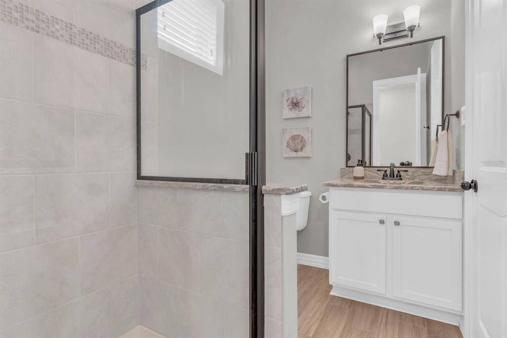 3/4 bath located between front room and laundry room features a custom tiled shower and coordinating vanity.