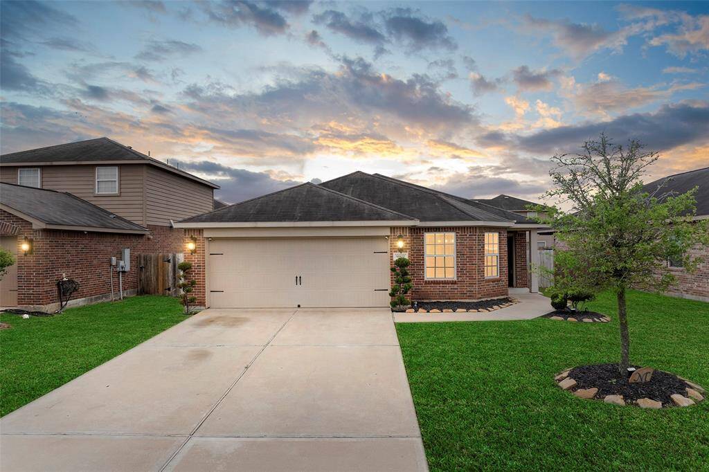 This charming brick home features a well-maintained front lawn, a two-car garage, and a welcoming covered entry. It's set in a suburban neighborhood with a fenced backyard, offering privacy and a cozy atmosphere.