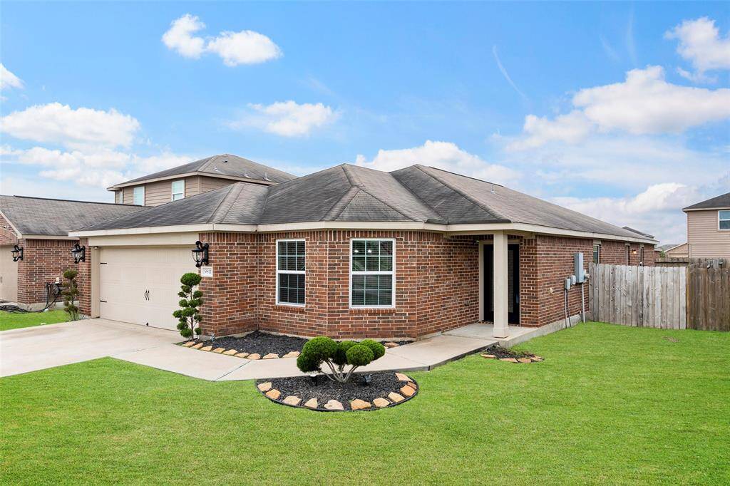 This photo shows the exterior of a single-story brick home with a clean, modern design. It features a welcoming front entrance with a glass door, well-maintained landscaping, and a two-car garage. The brickwork gives it a classic and durable appearance.