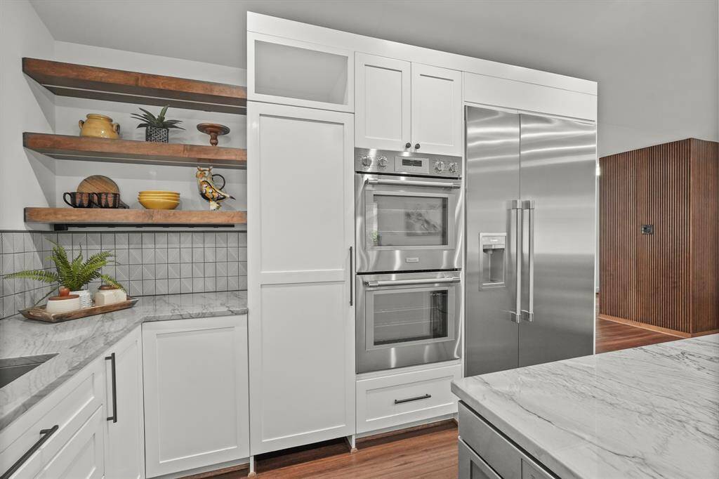 The custom wood shelves add a unique touch, offering both style & extra storage. Kitchen is equipped with top-of-the-line Thermador appliances. Be sure to look at the tucked away Pantry beside the ovens.