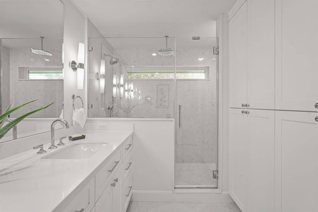 Primary En Suite Bathroom offers a light, bright atmosphere with neutral tones & modern finishes, & built-in cabinetry with sleek countertops, providing ample storage & a polished look.
