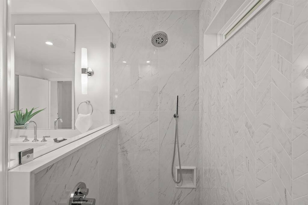 The large Walk-In Shower features stunning herringbone tile, complemented by a luxurious rainshower head for a spa-like experience.