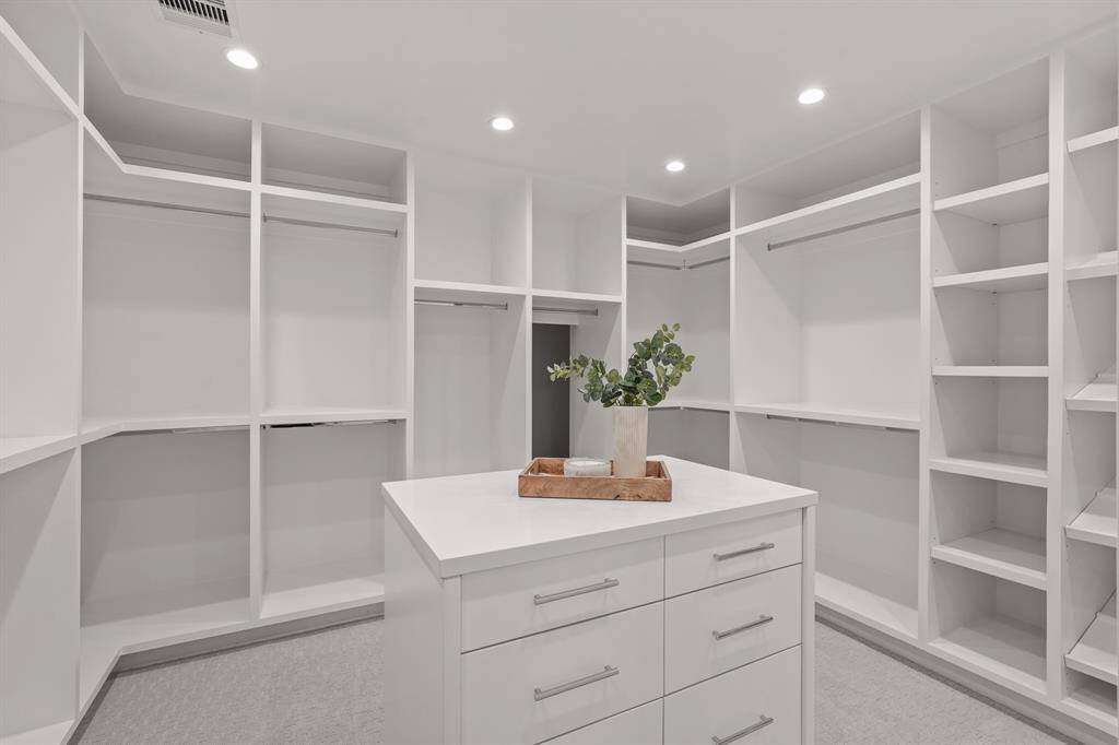 The Primary Suite features a spacious & luxurious custom walk-in closet, with an elegant island dresser that adds both style and functionality to the room.