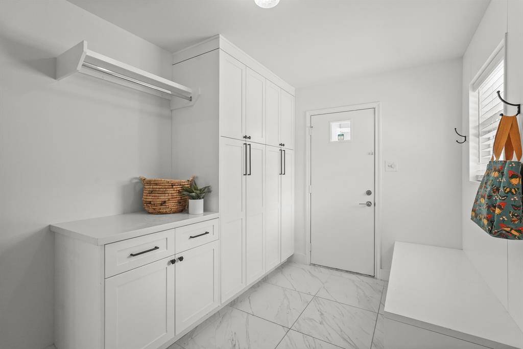 Utility Room features custom-built cabinetry, & provides ample storage space for laundry essentials, cleaning supplies, & more.