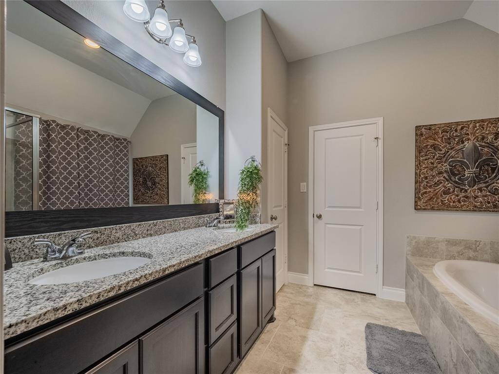 Primary bath has granite counter top, double vanities, tile flooring , beautiful framed mirror