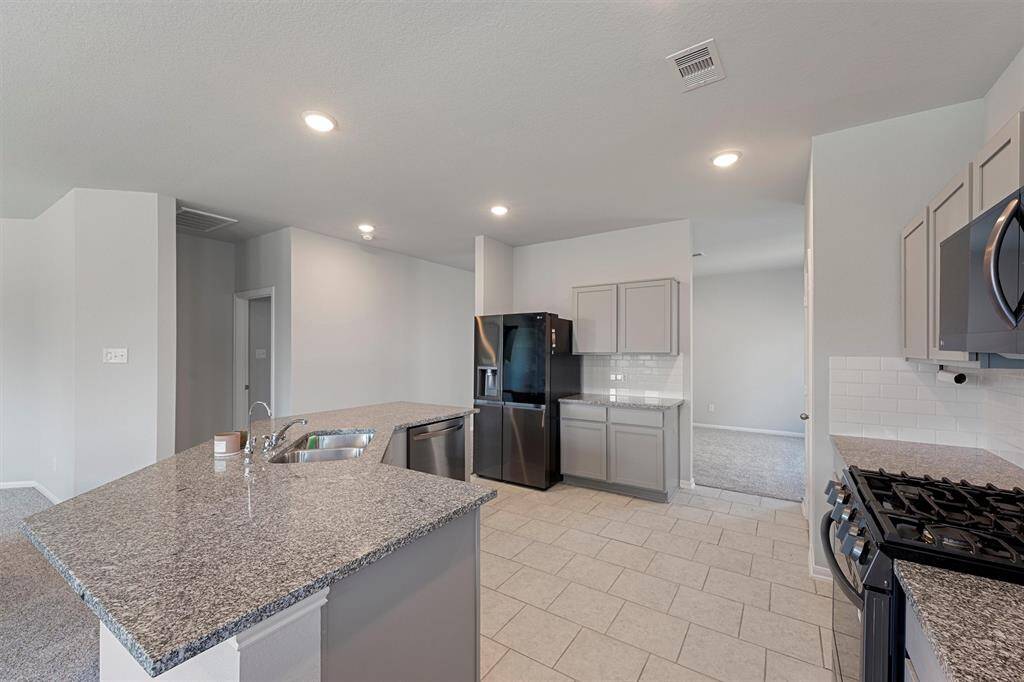 Modern kitchen featuring granite countertops, subway tile backsplash, stainless-steel appliances, and an oversized island perfect for entertaining.