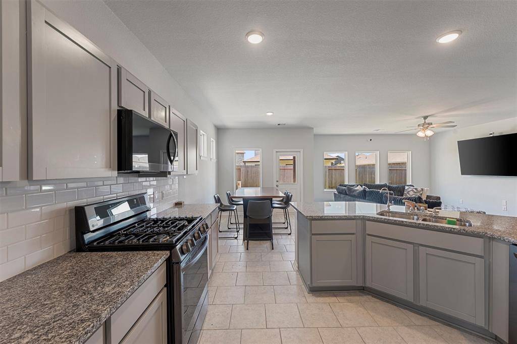 Spacious kitchen with granite island, stainless steel appliances, and modern gray cabinetry.