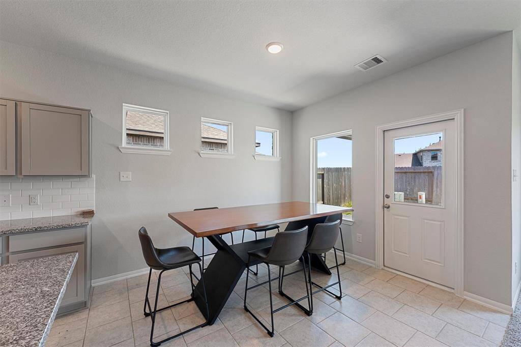Bright breakfast nook and living space with large windows and backyard views.