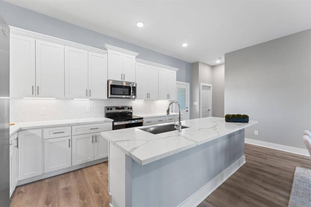 Stunning kitchen with quartz countertops, ample cabinetry, and stainless steel appliances included.