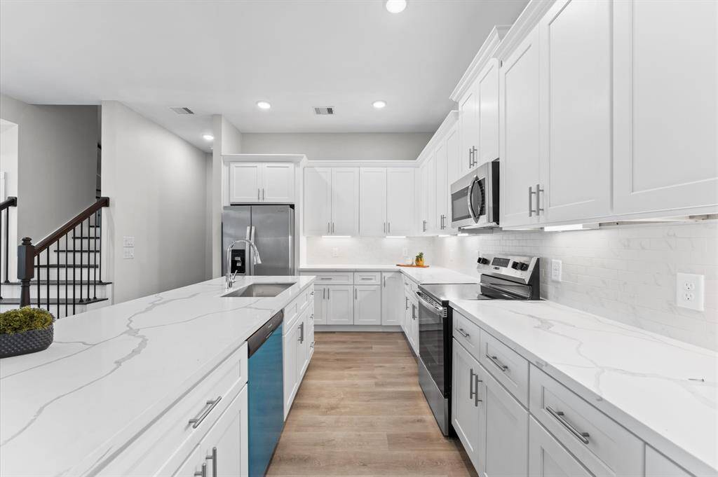 Stunning kitchen with quartz countertops, ample cabinetry, and stainless steel appliances included.