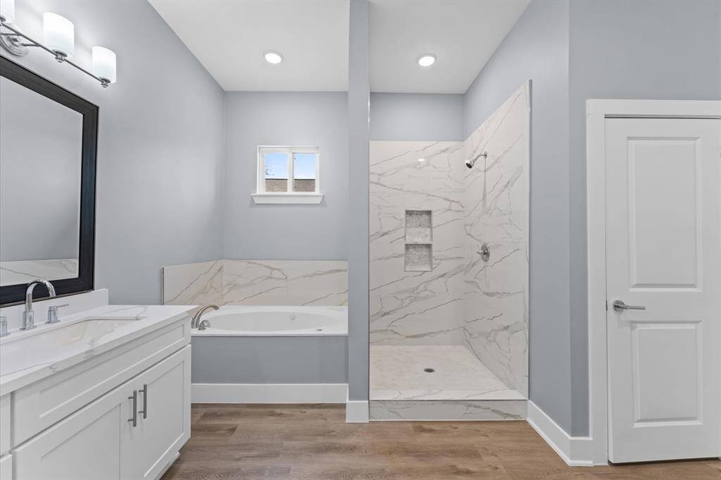 Spa-like bathroom with double sinks, soaking tub, separate shower, and walk-in closet.
