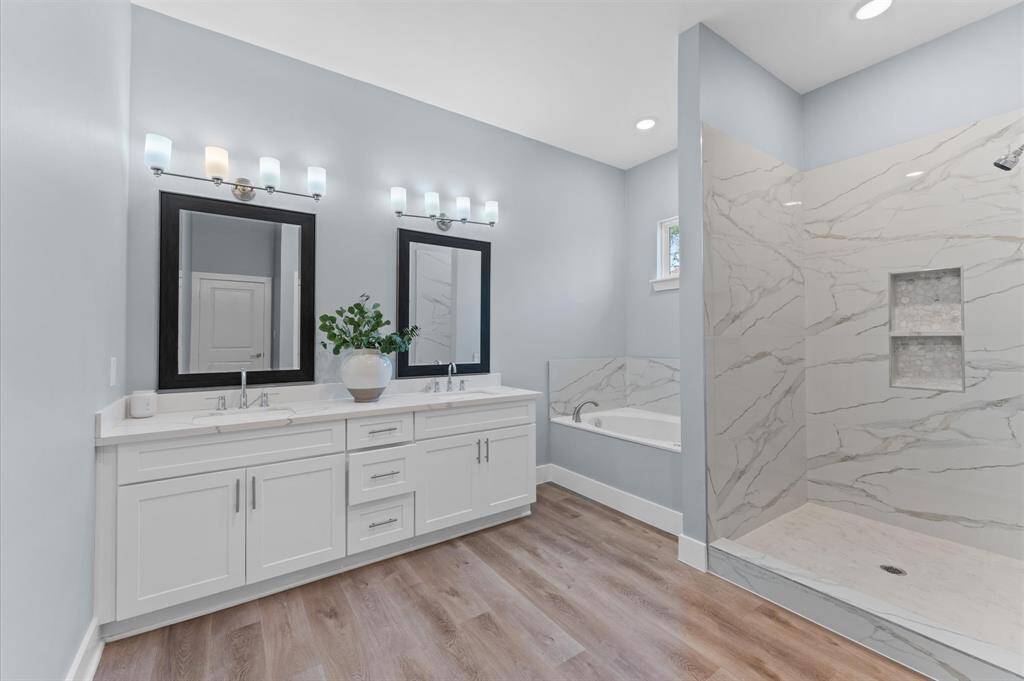 Spa-like bathroom with double sinks, soaking tub, separate shower, and walk-in closet.