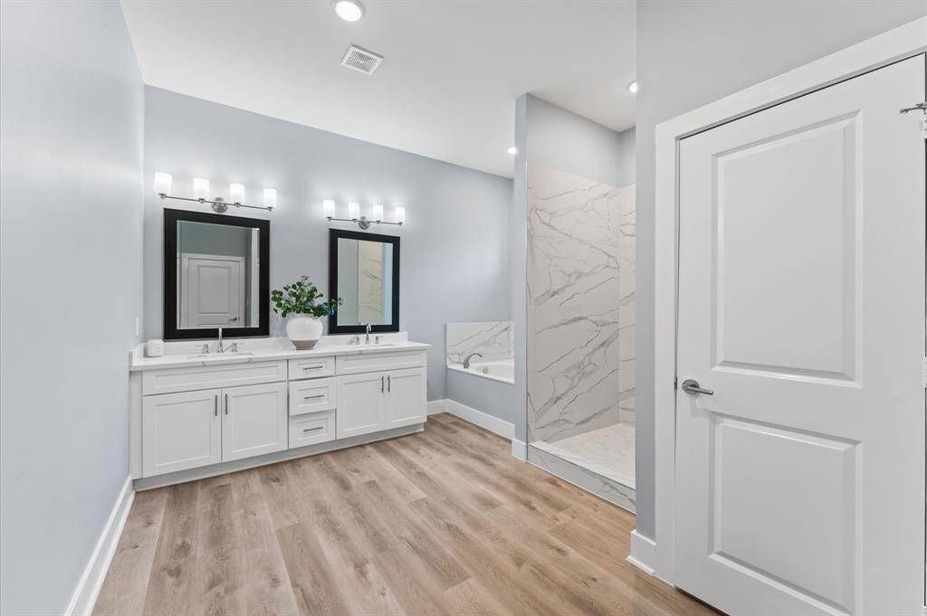 Spa-like bathroom with double sinks, soaking tub, separate shower, and walk-in closet.