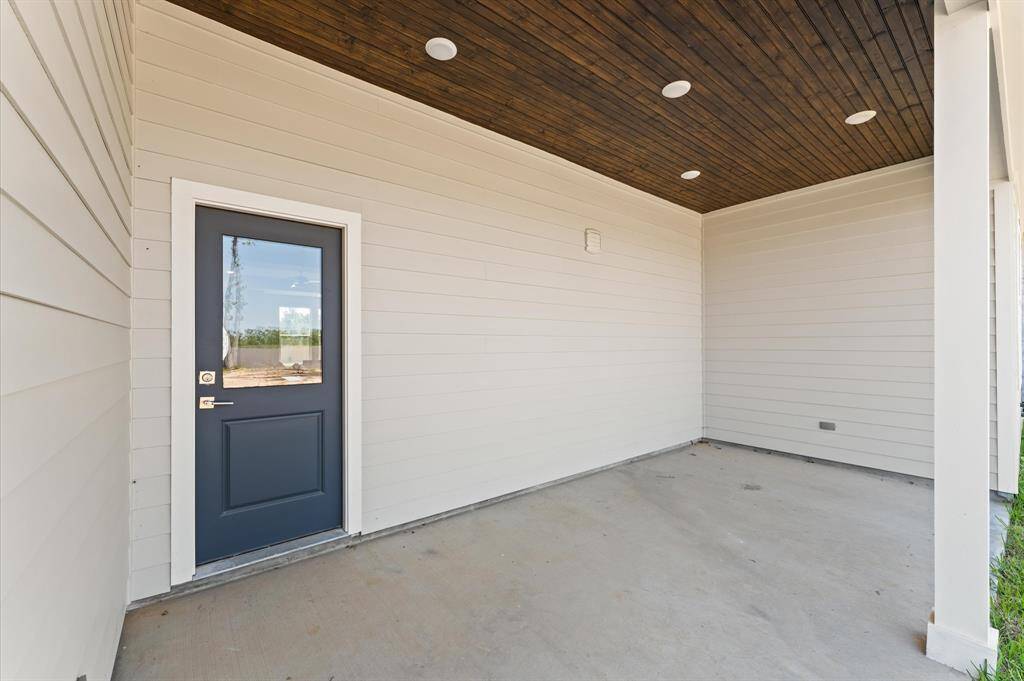Covered patio with wood-accented ceiling, ideal for grilling or outdoor lounging.
