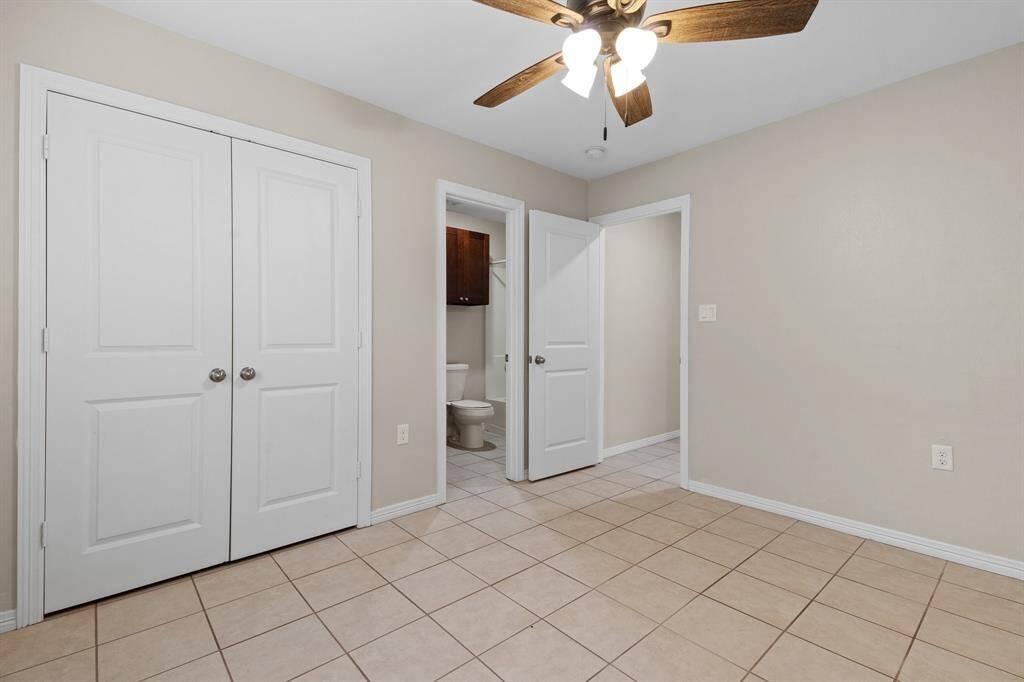 The room features tiled flooring, neutral wall colors, a ceiling fan, and includes a double door closet and an en-suite bathroom.