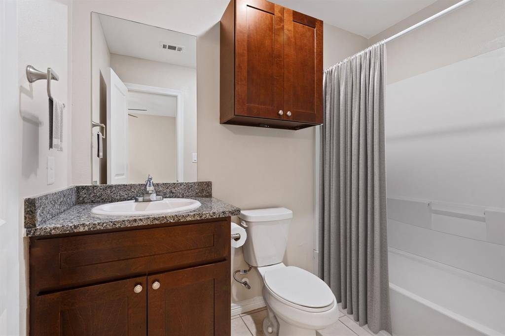 This is a modern, well-maintained bathroom featuring a vanity with granite countertop, under mount sink, large mirror, and a full tub. There's also a toilet, and the space has neutral color tones.