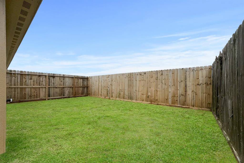 This is a spacious, private backyard offering a generous area for outdoor entertaining  or landscaping potential, viewed from a covered patio area.