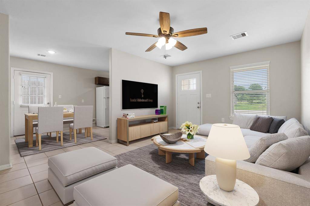 This is a bright and airy open-concept living space featuring a comfortable seating area perfect for a large couch and presents a modern ceiling fan. The room seamlessly transitions into a dining area with a din9ng space perfect for meals. The neutral color palette and ample natural light create a welcoming atmosphere.