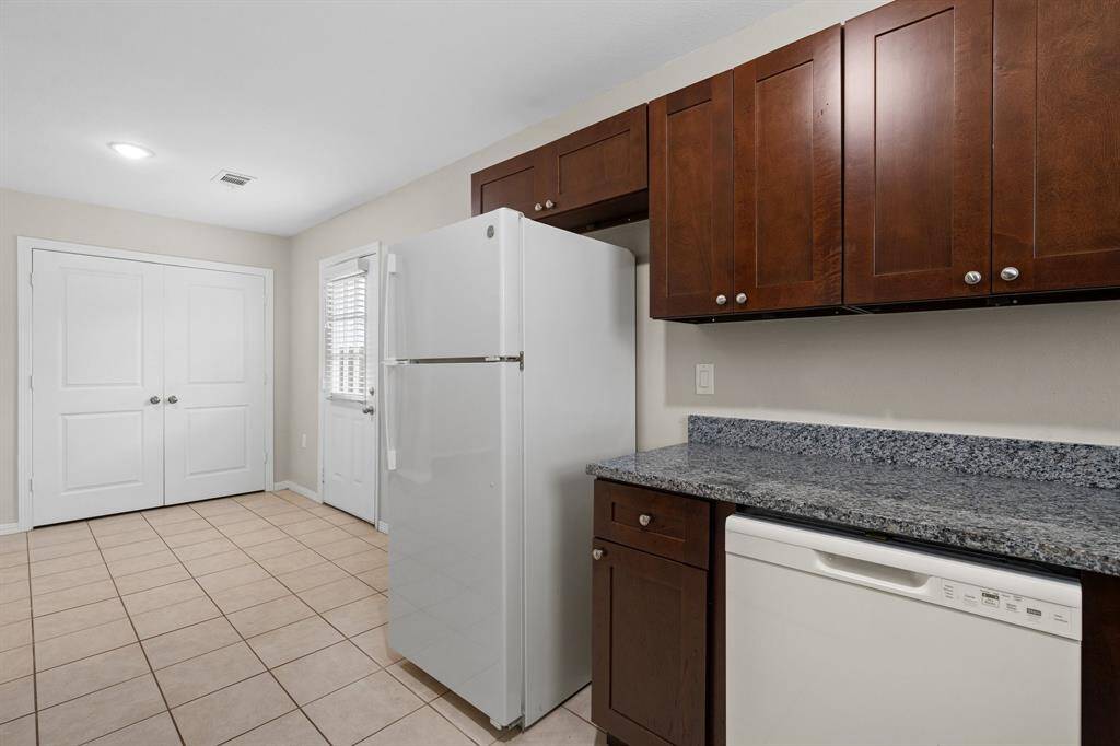 This is a clean, well-lit kitchen featuring modern appliances, granite countertops, and a plethora of  w cabinetry. There's tile flooring and a neutral color scheme that can easily match any decor.
