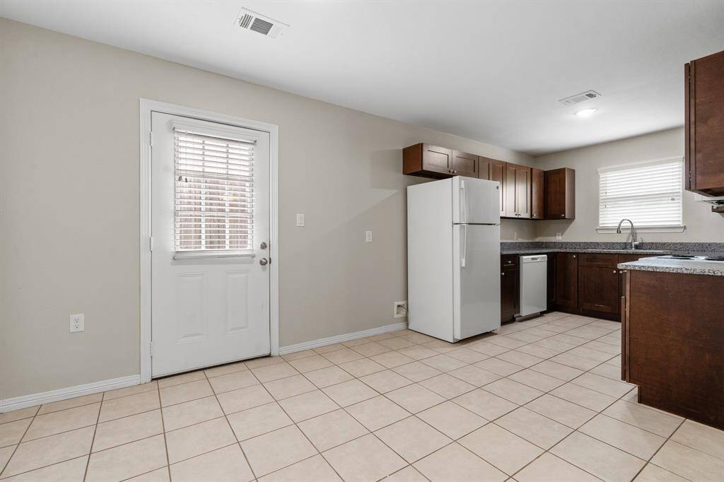 This is a tidy kitchen space featuring modern appliances, generous cabinetry, tile flooring, and a back door with an inset window for natural light.