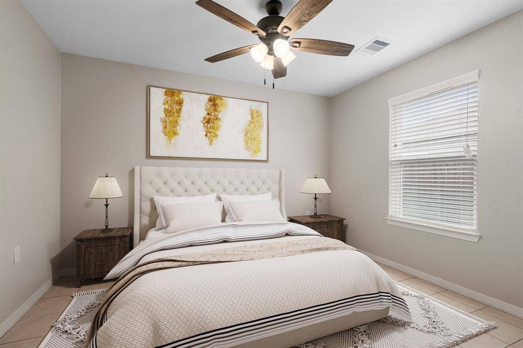 This is a well-lit, cozy bedroom featuring a large window with blinds. Neutral tones and a nuetral decorative palate to create a serene atmosphere.