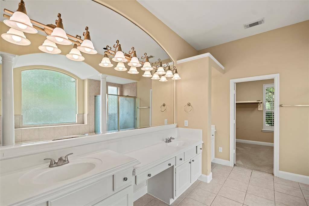 Luxurious primary bathroom featuring elegant double sinks and a spacious vanity.