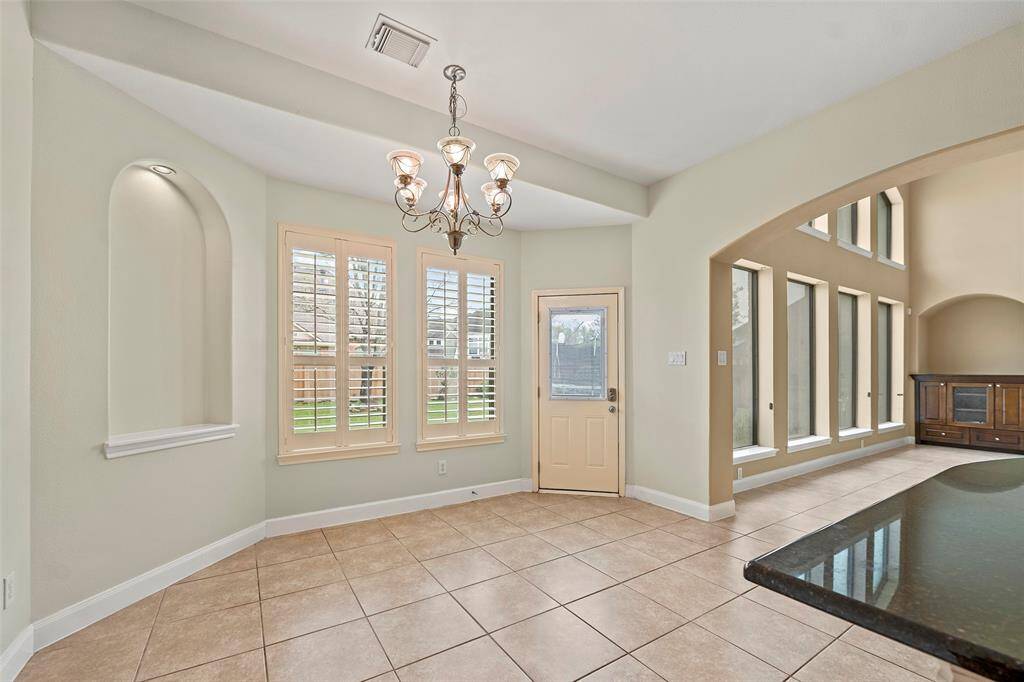Bright and spacious breakfast area with large windows and tile flooring, featuring a stylish chandelier. and illuminated alcove.