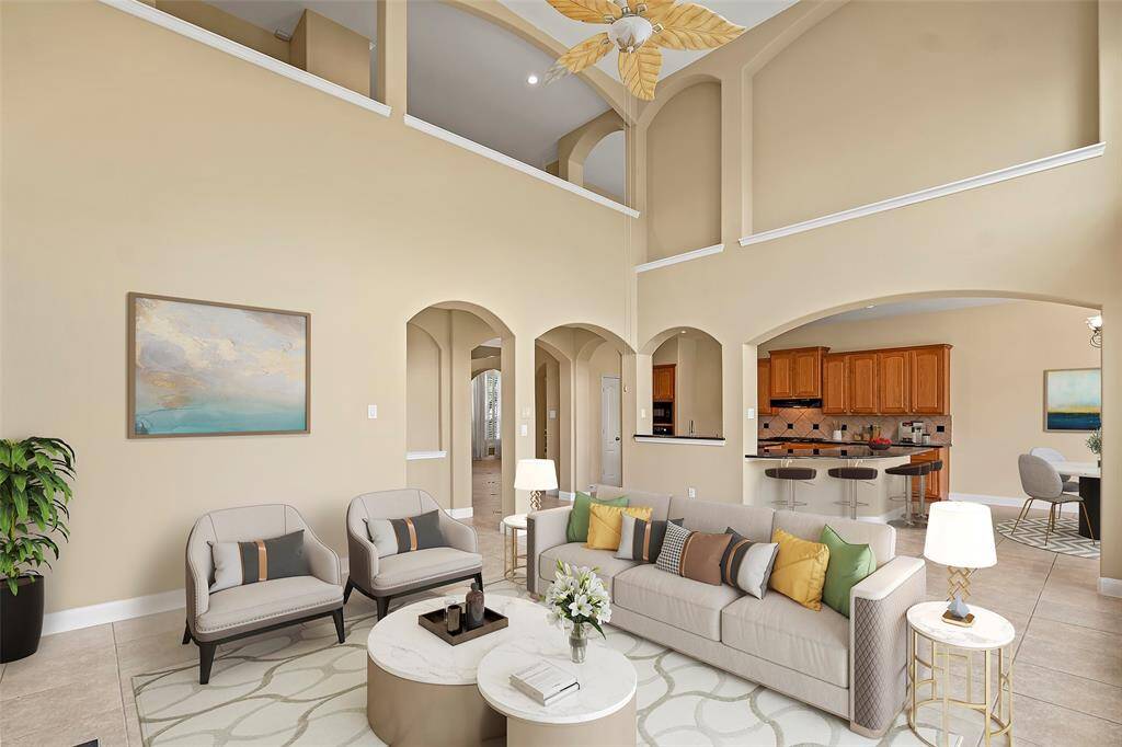 Spacious living room with high ceilings, large windows for abundant natural light and backyard views, cozy fireplace with elegant built-ins, and tiled flooring. Virtually staged!!